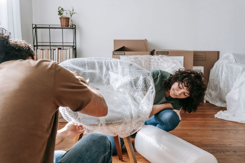 Movers wrapping furniture carefully inside a Stamford apartment