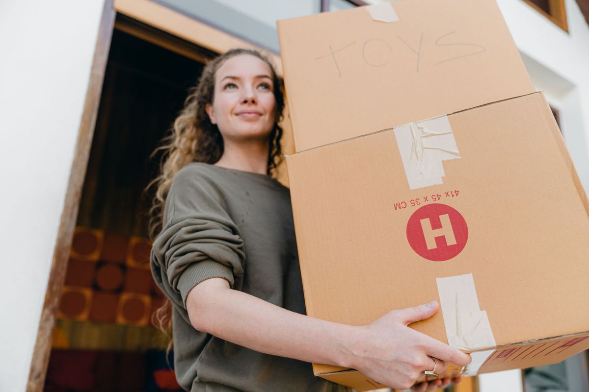 Friendly local movers carrying labeled boxes into a new home