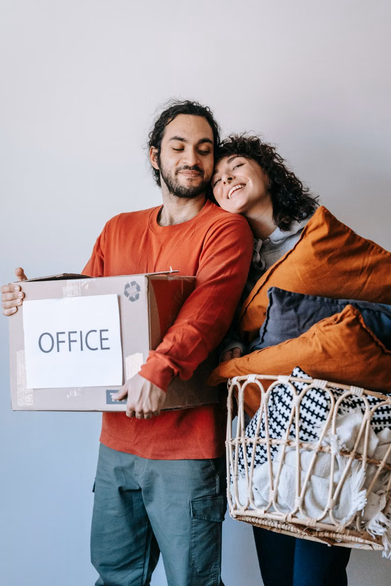 Happy couple standing among boxes in their new home